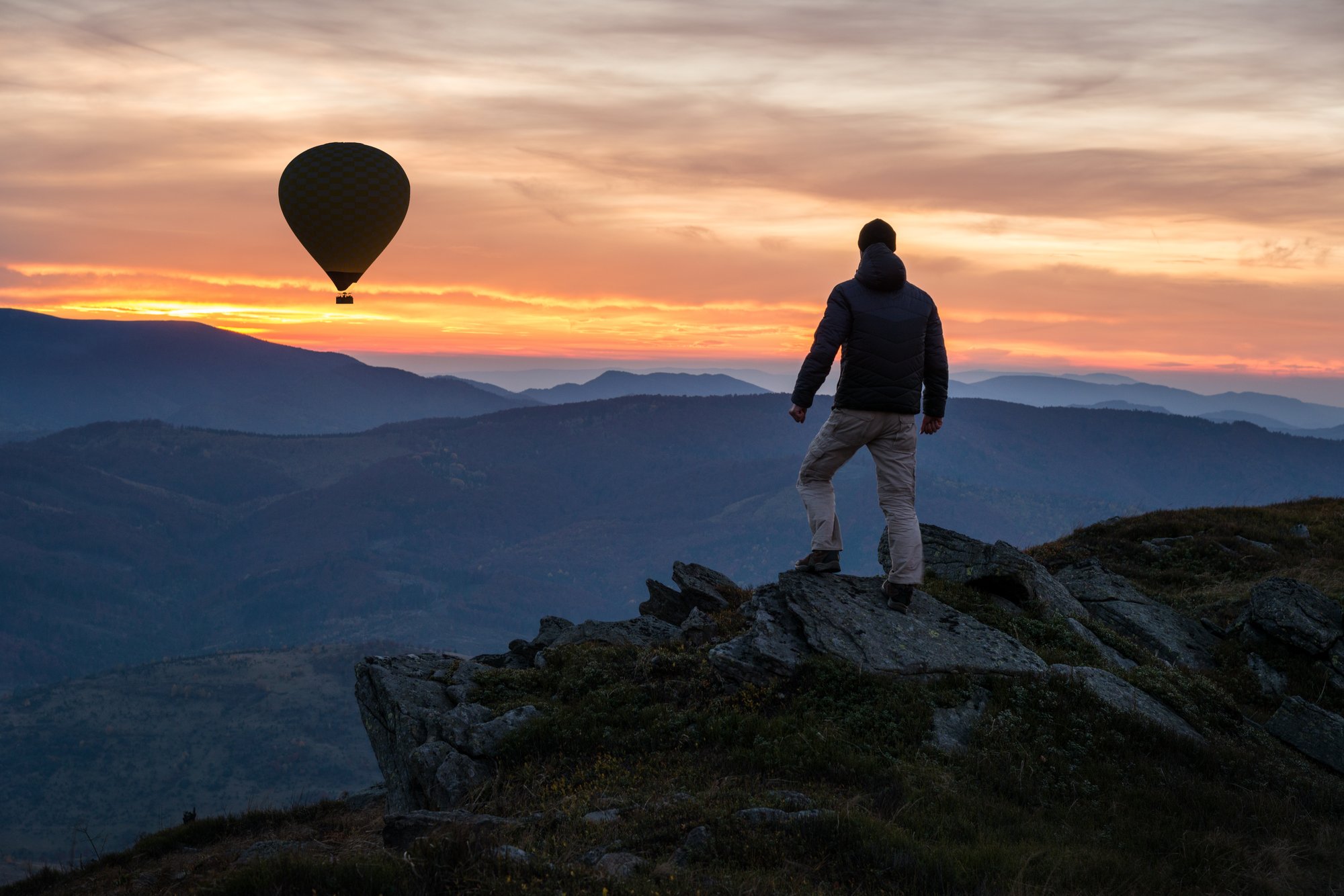 Full-Size_Hiker-on-mountain-peak-with-air-balloon-at-sky-sunset-sundown-20231213-GLO-EN